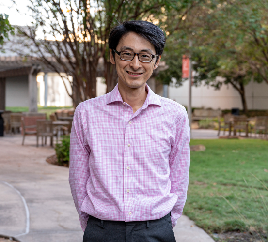 Man stands in outdoor courtyard.