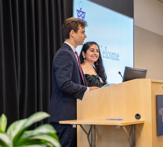 Two people in formal attire stand behind a podium.