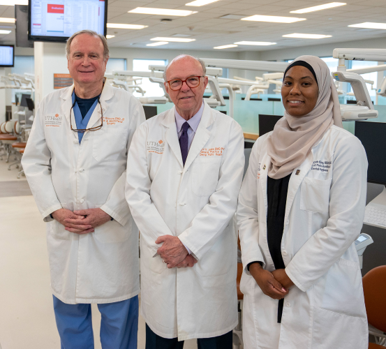 Three lab-coated individuals posed inside a simulation laboratory.