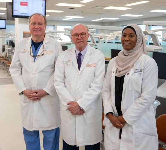 Three lab-coated individuals posed inside a simulation laboratory.