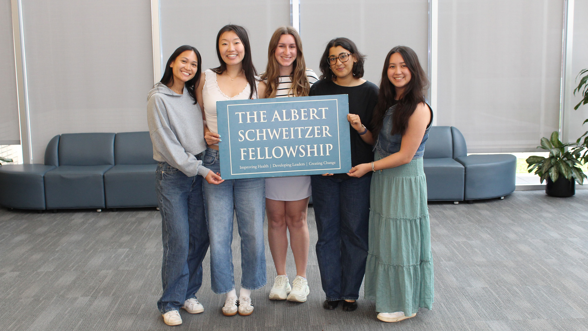 Five individuals pose with a sign reading “The Albert Schweitzer Fellowship.”