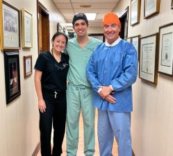 Three dentists in scrubs in a hallway.