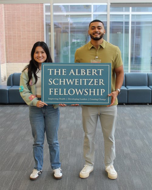 Two people co-holding a sign.