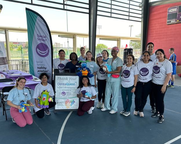 Group photo of 14 people holding stuffed animals to demonstrate proper dental hygiene.
