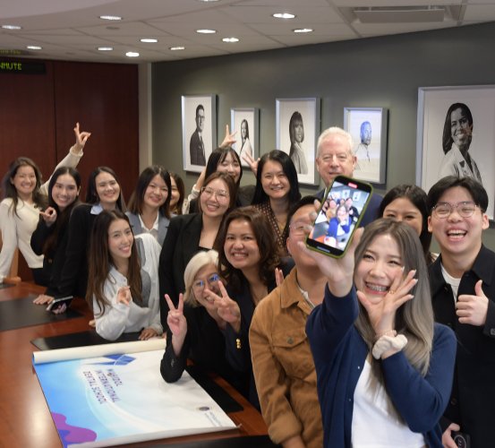 Woman taking group selfie on mobile phone in a conference room