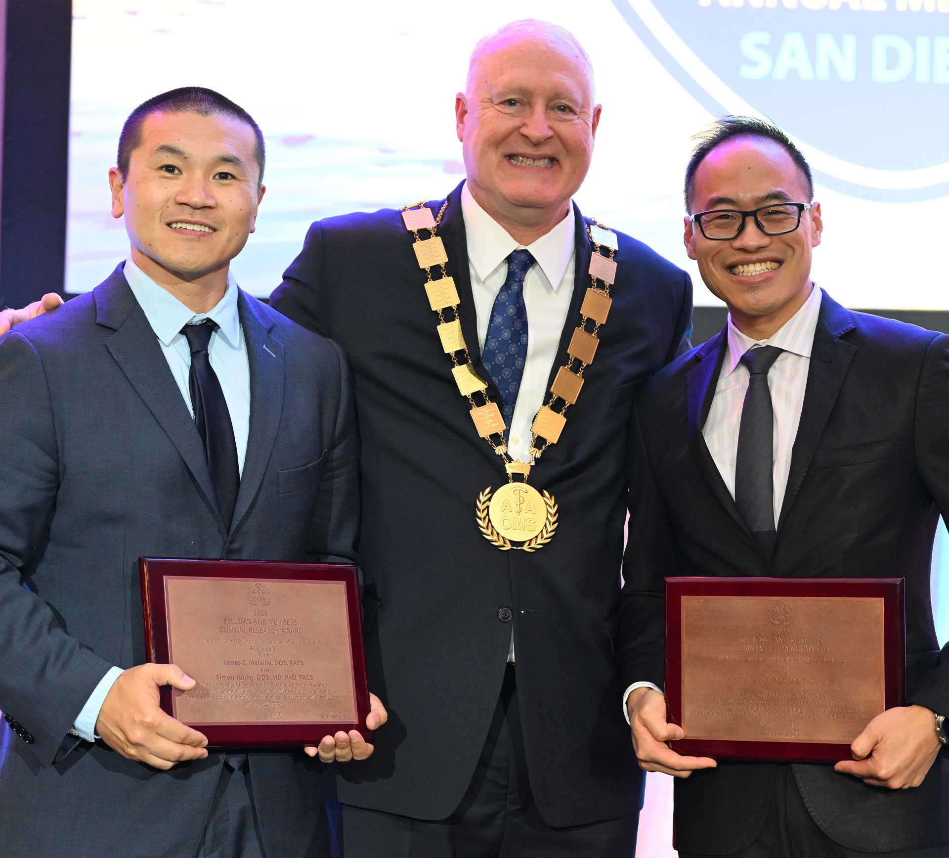 Drs. James C. Melville (left) and Simon W. Young (right) accepted the 2023 Clinical Research Award from American Association for Oral and Maxillofacial Surgeons 2022-23 President, Dr. Paul J. Schwartz.