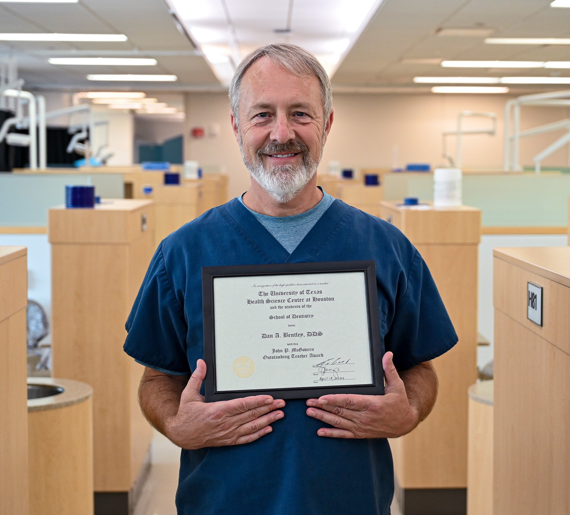 Dr. Dan Bentley holds his framed certificate for the John P. McGovern Outstanding Teaching Award inside his Red Practice.