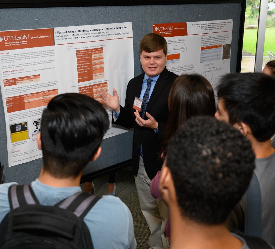 Dental student McCluer (Mac) Neuroth explains his research poster to a group of students.