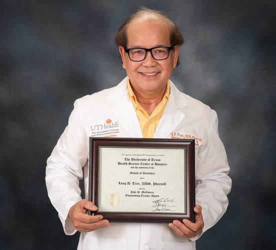 Dr. Long Tran holds his framed certificate for the John P. McGovern Award.