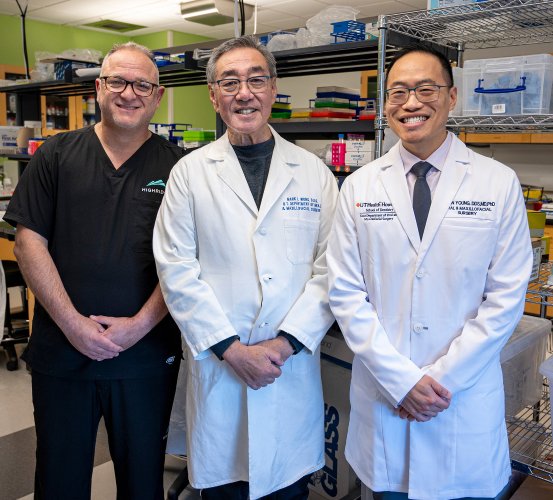 Three researchers in lab coats and scrubs stand in a research lab at UTHealth Houston School of Dentistry.