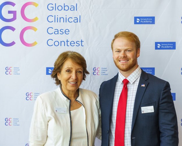 Two people looking at the camera in front of a backdrop.