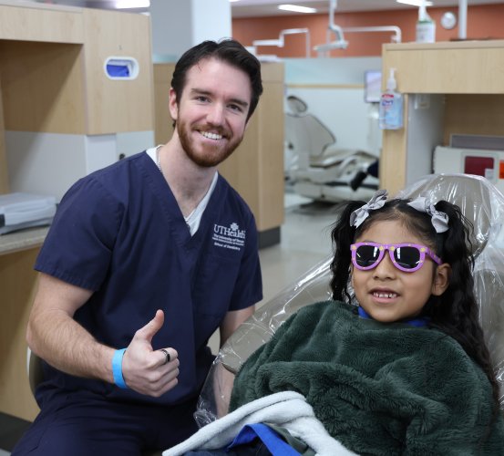 Dental student and child patient sit in a dental operatory.