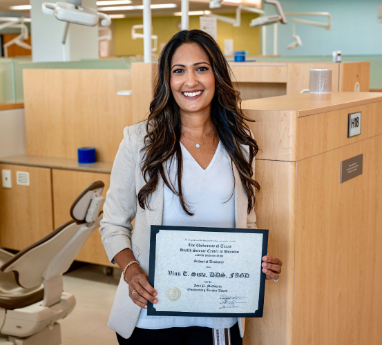 Person professionally dressed holding an award in a dental clinic.
