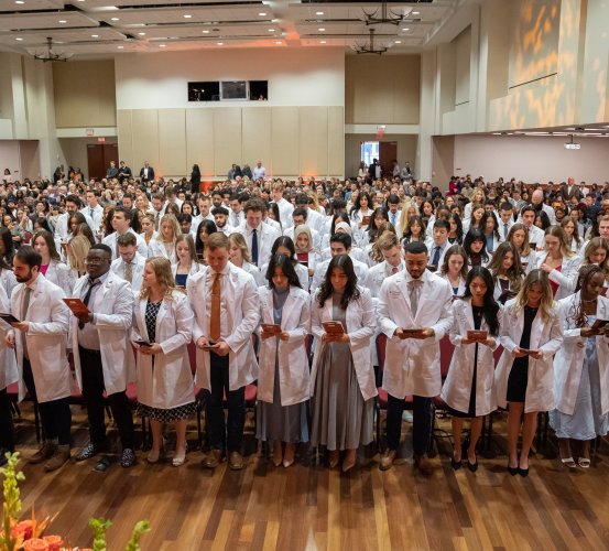 Dental students stand in a large event space.