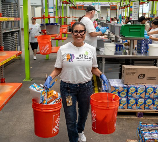 Woman carries orange buckets during a volunteer shift at a food bank.