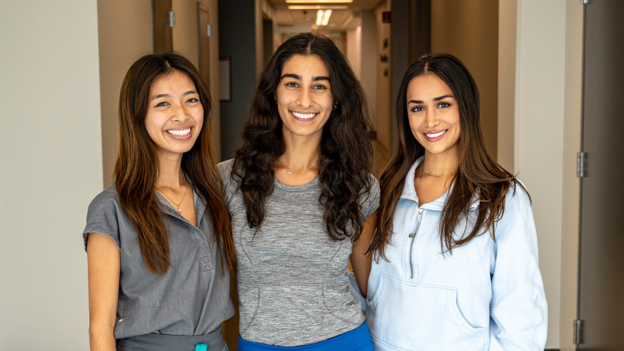 Three female dental students stand in a hallway.