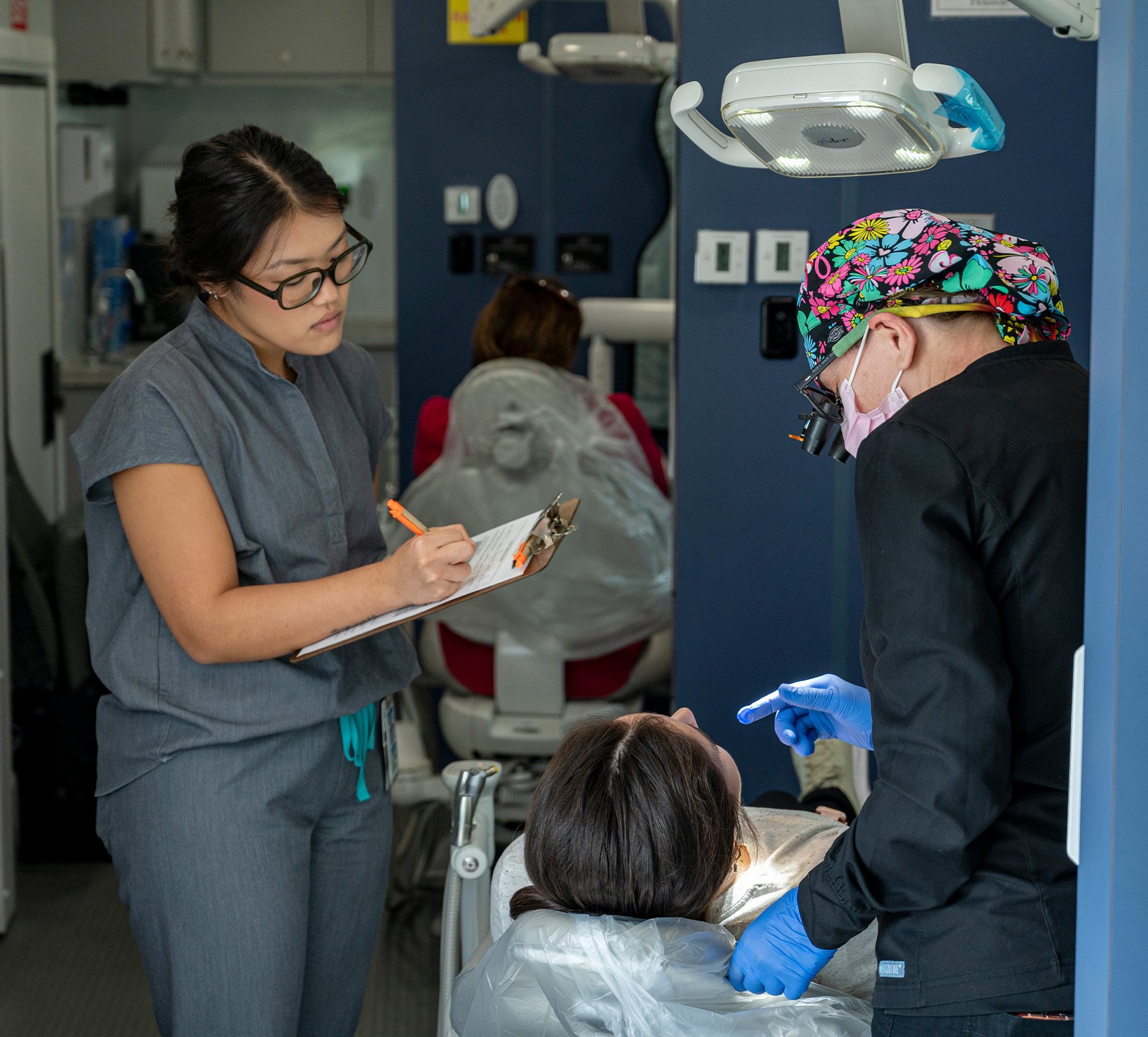 Group standing behind a table with dental products and brochures at an indoor event.