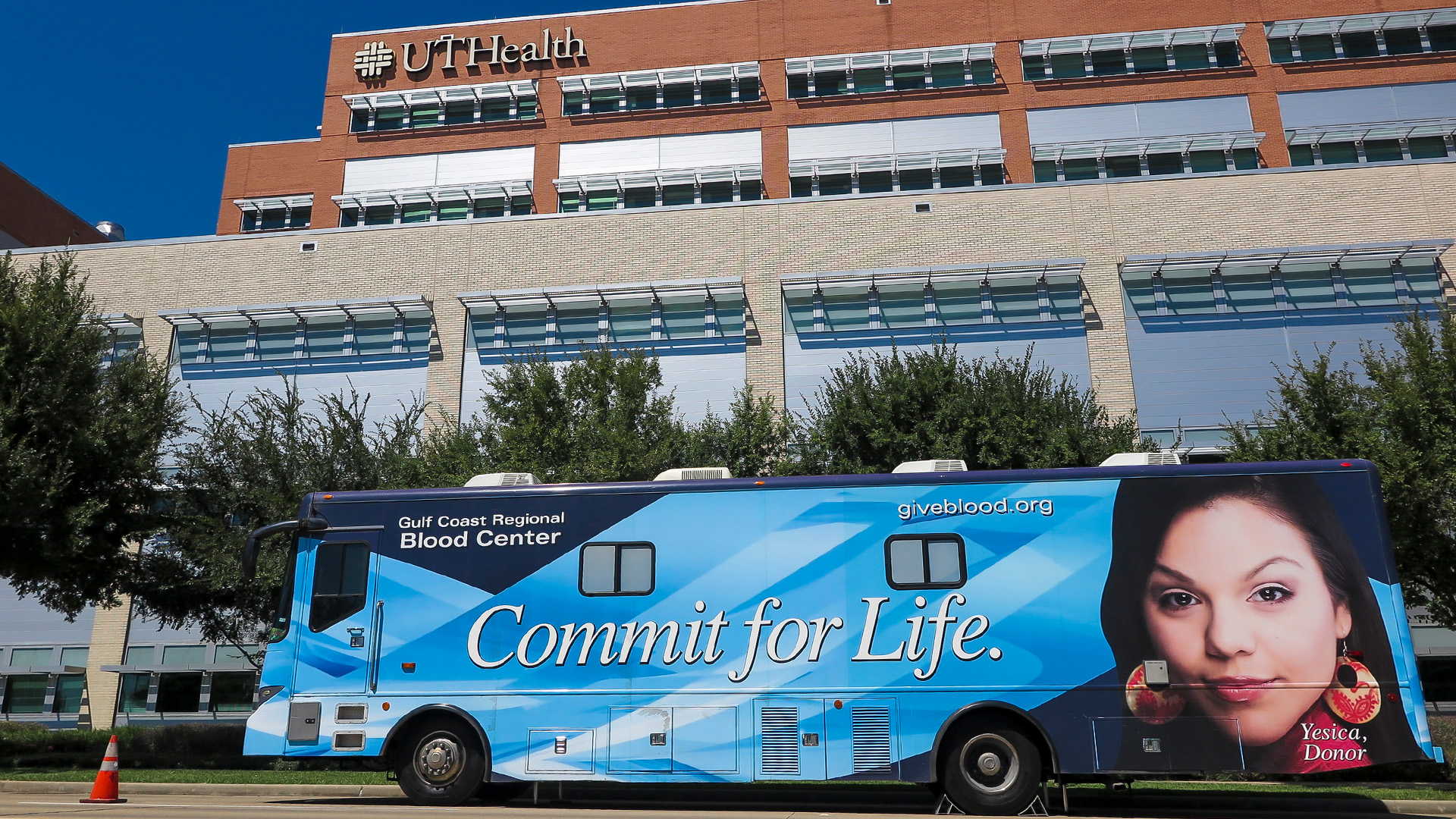Blue coach bus sits parked in front of a building.