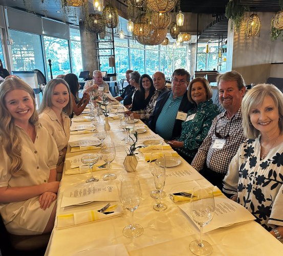 Former students convene at a dinner table.