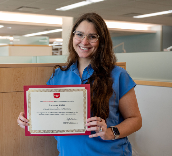 Person holding a framed dental award in an office.