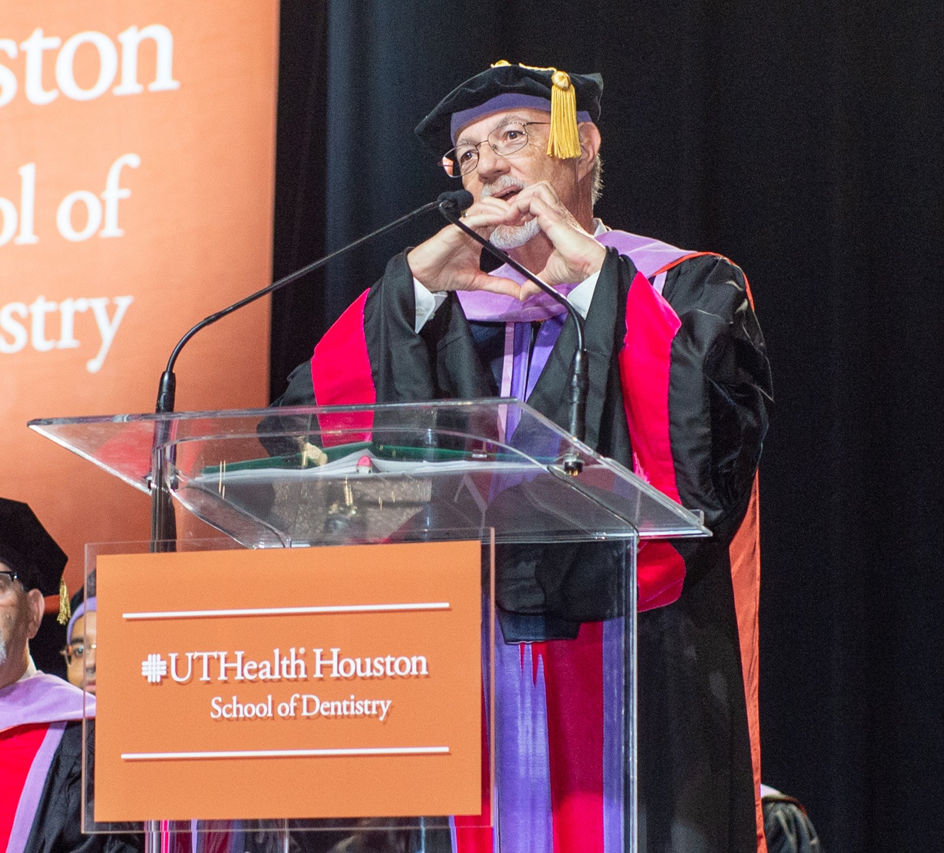 Scott R. Makins, DDS ’80, MS, makes a heart shape with his hands while delivering the inspirational message at UTHealth Houston School of Dentistry’s 119th Commencement Ceremony.