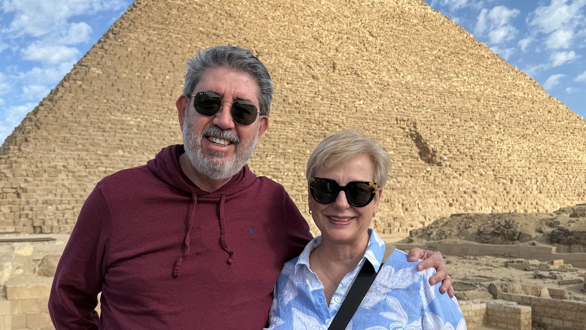 Man and women pose for a photo in front of a pyramid.