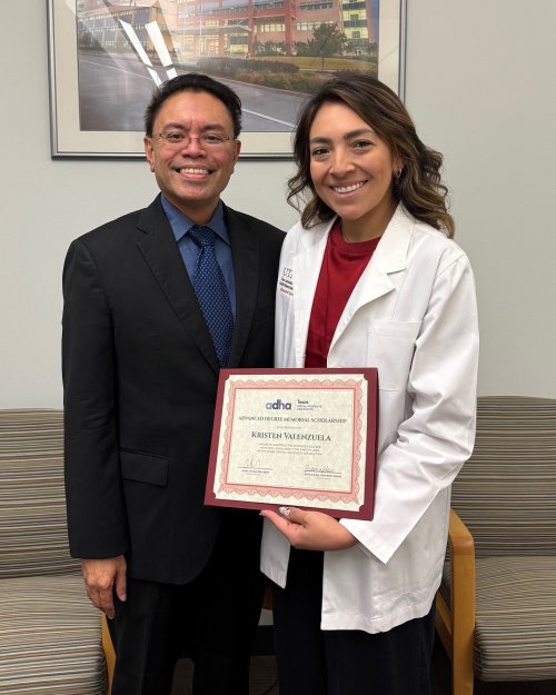 Two professionals pose with a certificate.