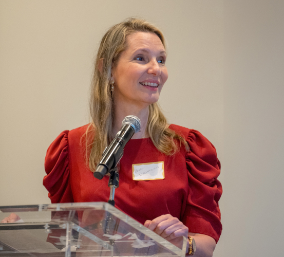 Person in red dress speaking at a podium.