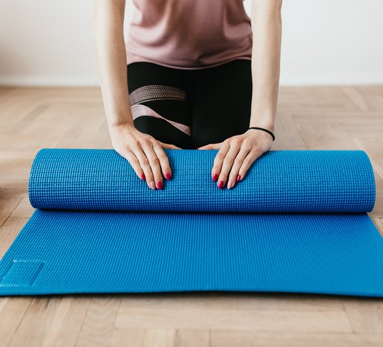 Closeup of female hands unrolling a yoga mat.