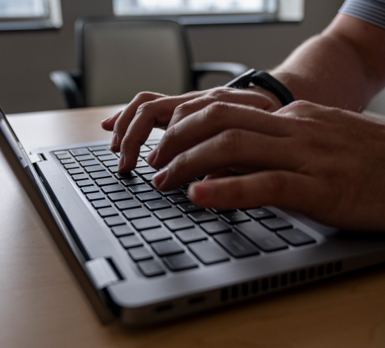 Hands typing on a laptop in an office.