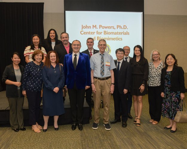 A group of individuals pose for a photo in front of a screen.
