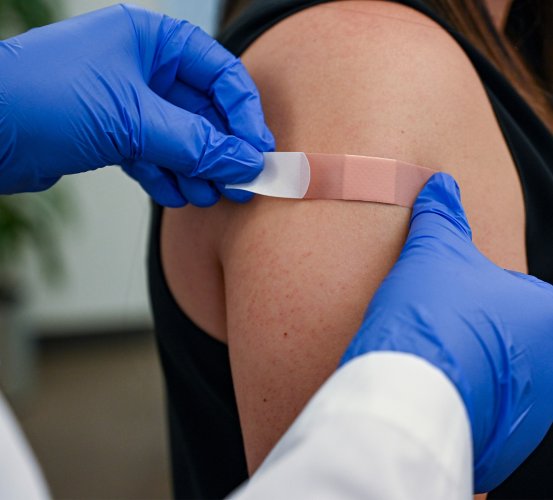 Doctor bandages a patient's arm after a vaccination.