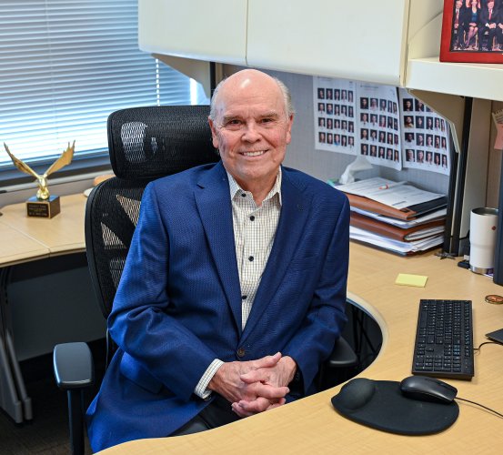 Man poses seated at his desk.