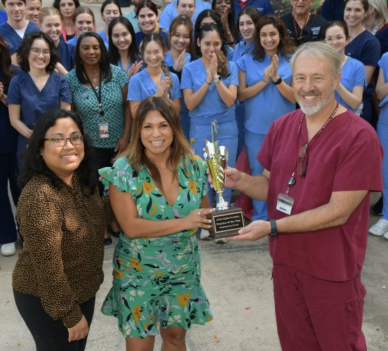 A group of dental professionals pose with a trophy.