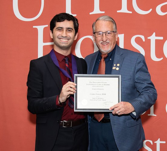 Dr. Stephen Laman (right) presented his framed certificate for the John P. McGovern Outstanding Teaching Award by Student Council President Ali Al Hatem during the annual DDS Senior Awards.