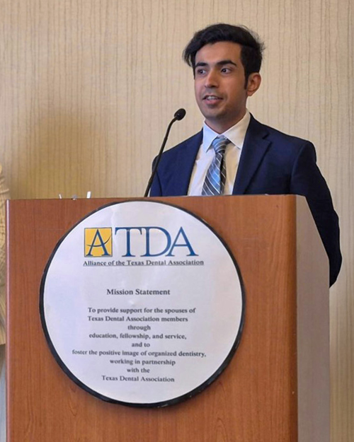 Man speaks at a podium in professional dress.
