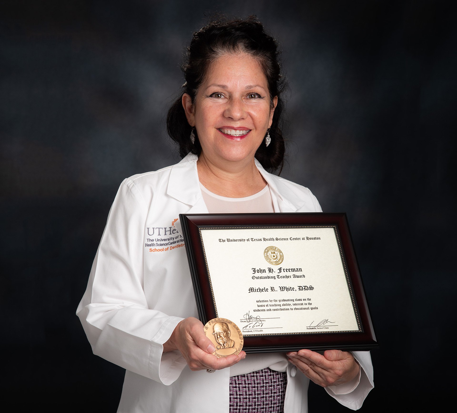 Dr. Michele White holds her framed certificate and medallion for the John H. Freeman Award.