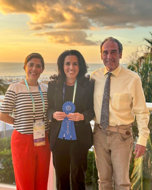 Woman holds her award ribbon with two people on either side during sunset.