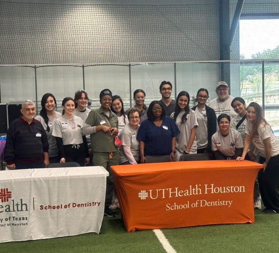Group of volunteers pose for a photo behind two tables.