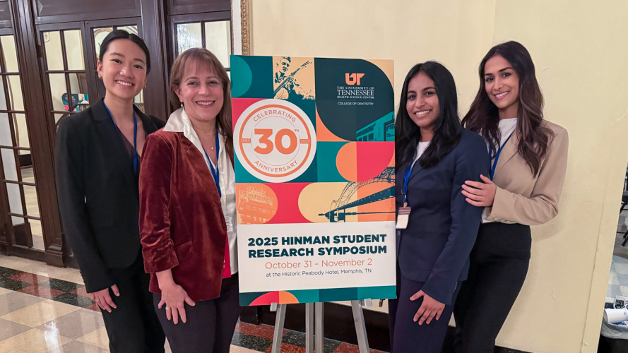Group of attendees standing next to a colorful sign for the 30th Annual Student Research Symposium.