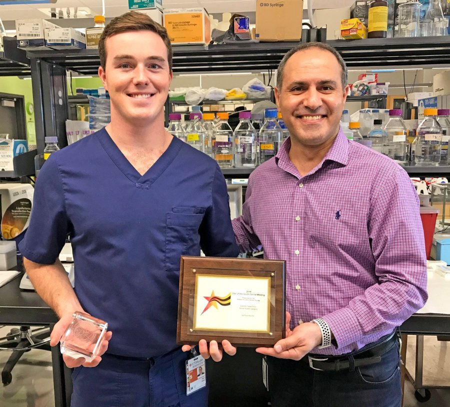 Dental student Kent Healy, mentored by Dr. Walid Fakhouri (right), hold the award and plaque from the 2019 Star of the South Scientific Table Clinic.