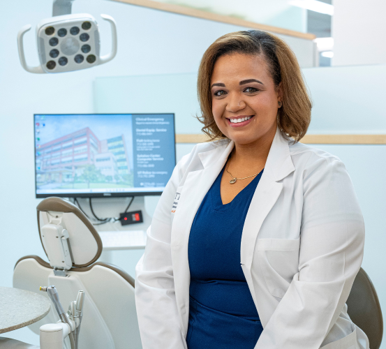 Dental students in scrubs and white coat seated in a dental operatory.