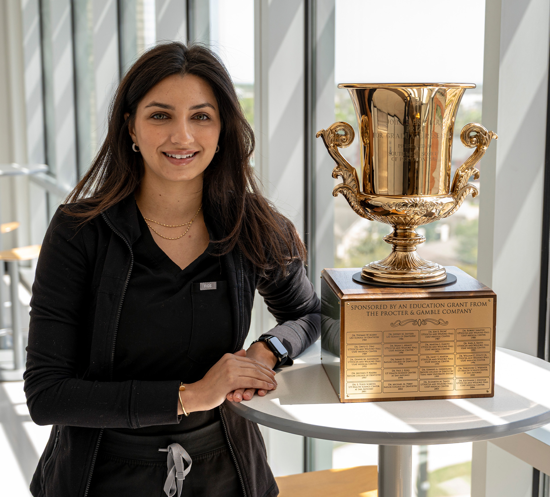 Doctor poses with a large trophy on a table.