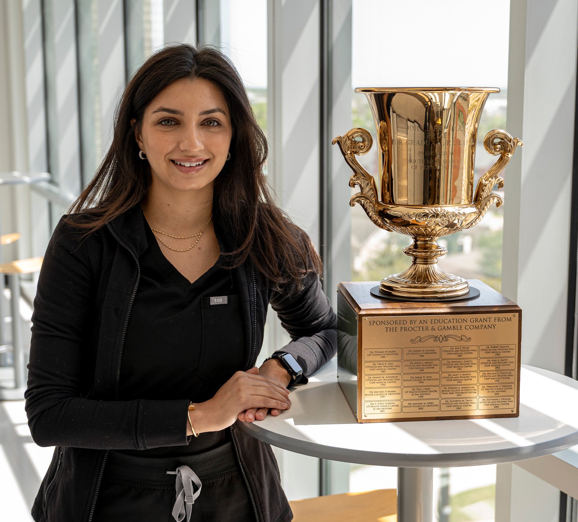 Doctor poses with a large trophy on a table.
