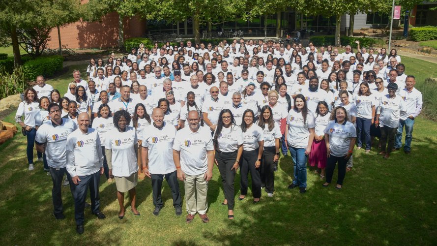 Large outdoor group photo of employees wearing the same white t-shirt.
