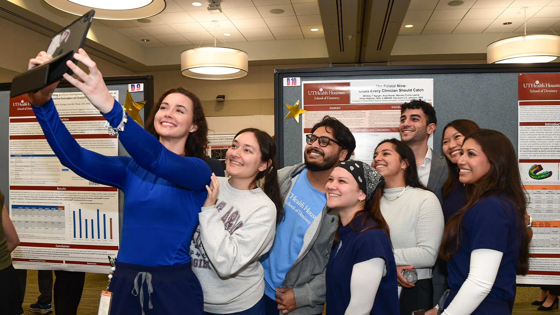 People pose for a selfie at an indoor event with display boards behind them.