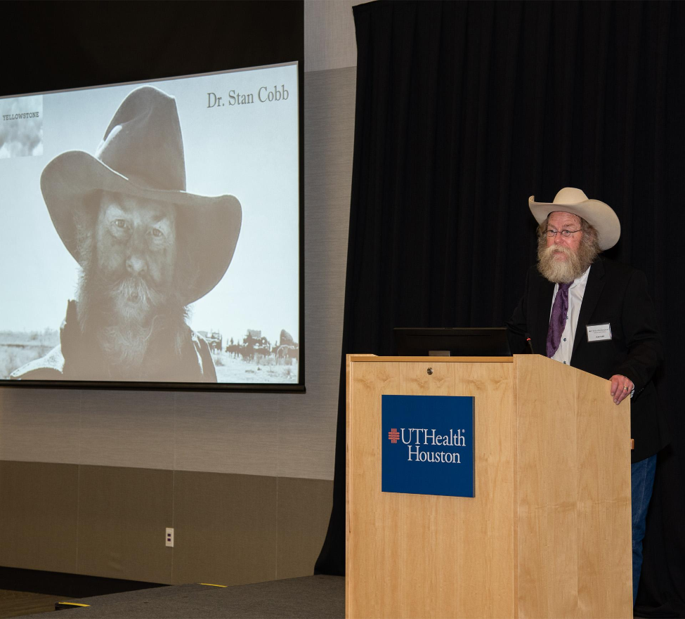 Keynote speaker Stan Cobb, DDS, address guests as an image of himself on the set of Paramount+'s