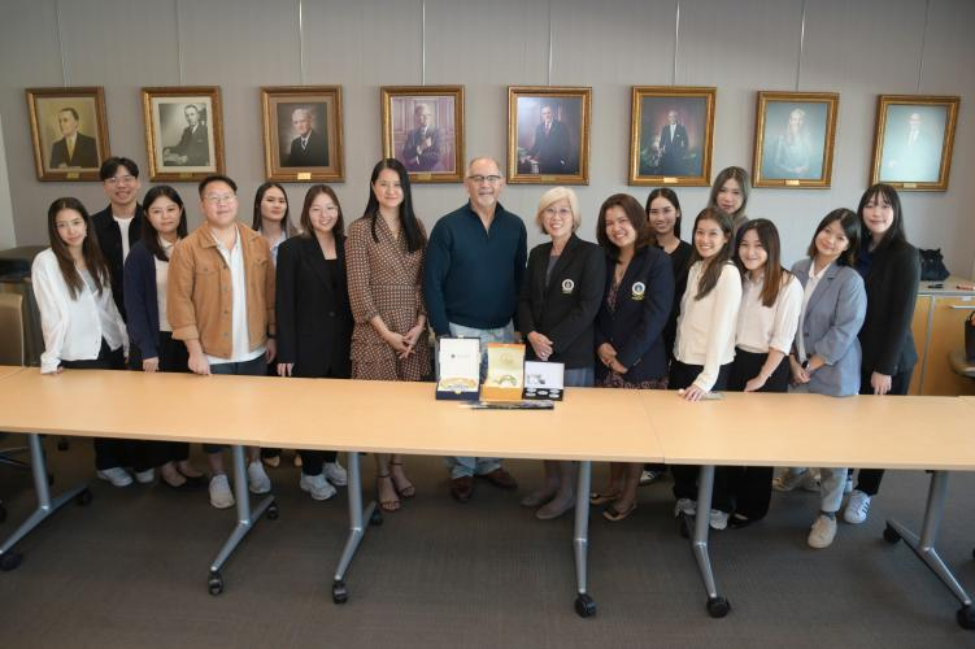 Group of people in professional business attire, presenting a gift in a conference room.