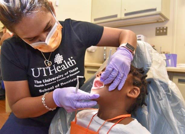 UTHealth dental hygiene student examines a child in the dental van. UTHealth dental hygiene student examines a child in the dental van.