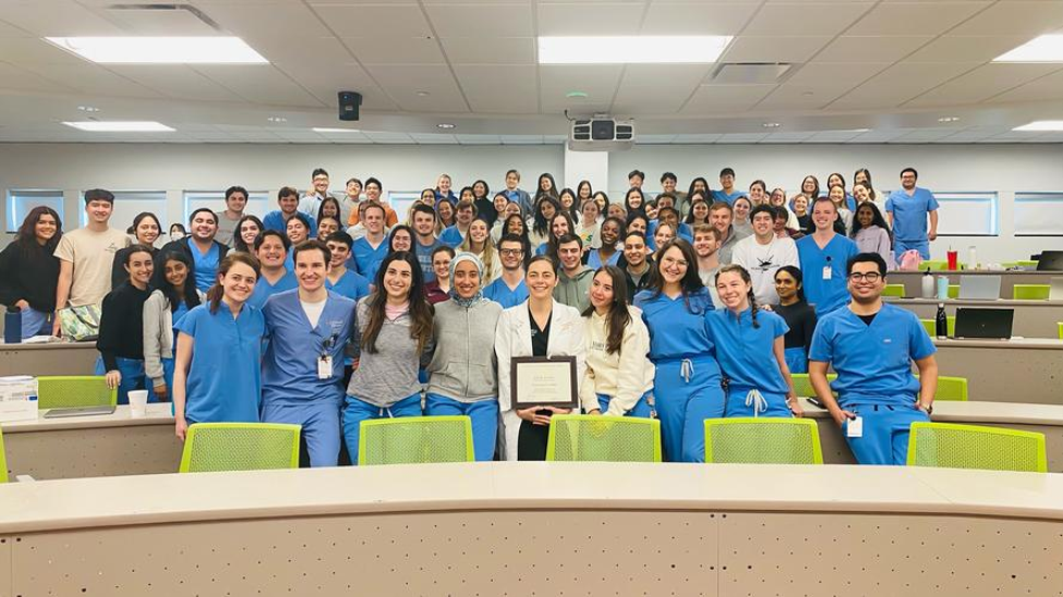 Dr. Juliana Barros holds her John H. Freeman Award for Faculty Teaching with her Operative Dentistry I class.